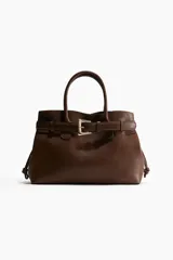 Bolso tote marrón con doble asa corta, cierre superior con cordón ajustable y cinturón decorativo con hebilla metálica dorada.