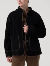 Chaqueta polar acolchada color azul marino, con diseño de rombos y ribetes en contraste color marrón. Presenta cuello alto, cierre frontal con botones y bolsillos frontales estructurados.