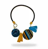 Collar de diseño artístico compuesto por una banda de cuero negro y diversos dijes de resina en formas geométricas y circulares, con patrones marmolados y a rayas en tonos azul, marrón y mostaza.