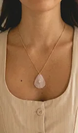 Collar de acero dorado con cadena fina y dije en forma de gota de piedra rosada con una estrella dorada y aplique brillante en el centro.
