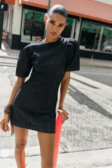 Vestido corto de denim oscuro con cuello redondo, mangas cortas abullonadas y costuras decorativas en contraste. Presenta un corte entallado y cierre posterior con cremallera oculta.