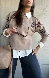 Sweater de punto color beige con cuello redondo y diseño de flores bordadas en tonos oscuros en el frente y las mangas.