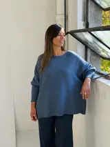 Sweater de punto color azul, con cuello redondo, corte holgado y mangas largas con puños ajustados.