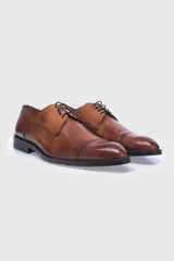 Zapato acordonado de cuero color marrón, con costura punteada en la puntera y suela de cuero.