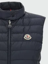 Chaleco acolchado Moncler modelo Igens, de diseño ligero y entallado. Presenta cierre frontal completo, cuello alto con broche a presión y el logo de la marca aplicado en el pecho.