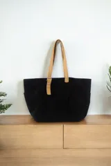 Cartera maxi negra de tela con asas de cuero color beige y bolsillos laterales.