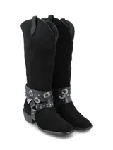 Bota alta de gamuza negra con diseño de inspiración western, taco cuadrado y puntera fina. Cuenta con arneses desmontables de cuero napa adornados con tachas y apliques metálicos alrededor del tobillo.
