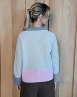 Cardigan de lana lambswool con diseño color block en tonos beige, marrón y turquesa. Presenta escote en V, cierre frontal con botones y puños anchos acanalados.