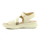 Sandalia de mujer color crema, con tira ancha sobre los dedos, tira cruzada sobre el empeine, pulsera con velcro al tobillo y plataforma baja.