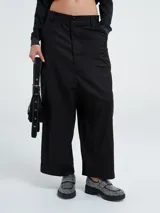 Pantalón negro tipo chino, de corte ancho, con botón y bolsillos delanteros.