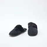 Pantuflas tipo mule de color negro, confeccionadas en material aterciopelado con detalle de borde en pelo sintético. Poseen suela plana y diseño abierto en el talón.
