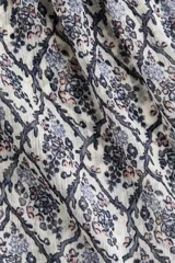 Top sin mangas de tejido liviano con estampado floreado en tonos azules y blancos, diseño con volados escalonados en el pecho y silueta evasé.