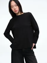 Top de manga larga color negro con cuello redondo, diseño de silueta holgada y tajos laterales en el ruedo. Presenta puños anchos estilo camisero.