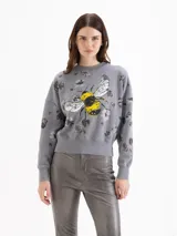 Buzo de algodón gris con estampa de abeja en el centro y diseño de flores oscuras dispersas por toda la prenda. Cuenta con cuello redondo, mangas largas y puños y cintura elastizados.