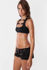 Microshort de gabardina de tiro bajo y corte slim fit. Presenta costuras en contraste color rojo, cierre metálico frontal y presillas largas en la cintura. La prenda cuenta con un proceso de sobreteñido y lavado artesanal que le otorga un aspecto desgastado único.