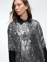 Vestido corto de corte recto y holgado, confeccionado en tejido cubierto de lentejuelas doradas. Presenta cuello redondo, mangas cortas amplias y una caída fluida.