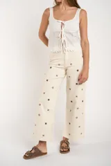 Pantalón de jean color crudo, de corte recto y tiro medio, con bordados de flores marrones.