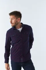 Camisa de manga larga confeccionada en pana de algodón con estampado de cuadros en tonos azul y bordó. Presenta cuello clásico, cierre frontal con botones y ajuste regular.