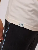 Remera negra de algodón con estampado en la espalda con palmeras, tabla de surf y texto en color blanco y fucsia.