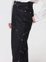 Pantalón de tiro medio y pierna ancha confeccionado en denim de algodón grueso. Presenta un diseño a rayas verticales en tonos azul y celeste, con costuras en contraste color rojo, bolsillos laterales tipo cargo y remaches metálicos.