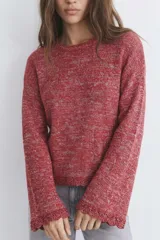 Sweater tejido de punto en color rojo con destellos de lurex. Presenta cuello redondo, mangas largas con terminación acampanada y detalle de borde festoneado en puños y ruedo.