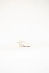 Sandalias tipo slingback color off-white con puntera abierta y taco cuadrado de altura media. Presentan una tira ajustable con hebilla en el talón.