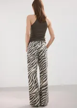 Jeans de corte wide leg con estampado animal print tipo cebra en tonos beige y negro, tiro medio y diseño de pernera ancha.