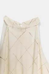 Vestido midi de cuello halter con diseño de cuadros, cintura elástica y abertura en la espalda. Cuenta con cierre de cremallera oculta y botón en la parte posterior.