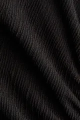 Vestido midi negro con textura, escote bote, mangas largas tipo trompeta y diseño ajustado con frunces laterales que generan un efecto drapeado.