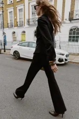 Camisa entallada color marrón oscuro, con cuello camisero y manga larga. Presenta dos bolsillos de plastrón en el delantero y cierre frontal con botones a presión dorados.