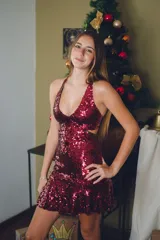 Vestido corto negro con estampado de plumas doradas, escote en V, breteles finos cruzados en la espalda, cut-outs laterales y volado en el ruedo.