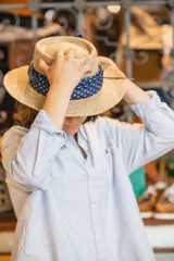 Sombrero de alga marina con ala mediana y cinta de tela azul con lunares blancos alrededor de la copa.