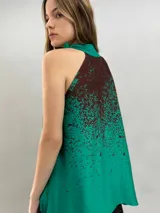Blusa de satén con escote halter y cuello elevado anudado lateralmente. Presenta un diseño estampado degradado en tonos verde esmeralda y azul, con corte holgado y caída fluida.