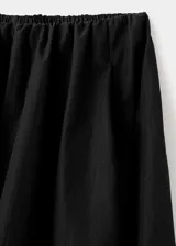 Falda larga de corte evasé en color negro, con cintura elástica y tiro medio. Presenta un diseño fluido y minimalista con bolsillos laterales ocultos.