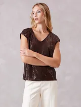 Blusa sin mangas con escote en V, confeccionada completamente en lentejuelas color dorado. Cuenta con forro interno a tono y un corte recto y holgado.