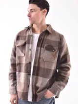 Sobrecamisa a cuadros azul y gris con cuello clásico, cierre frontal con botones, dos bolsillos con solapa abotonada en el pecho y puños abotonados.