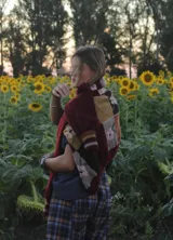 Saco tejido de punto con diseño de parches en tonos tierra, bordó y detalles florales. Presenta mangas largas con puños a rayas y una estructura estilo patchwork.