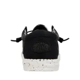 Zapatos Hey Dude Wally Canvas negros, tipo mocasín, con cordones elásticos y suela blanca con motas negras.