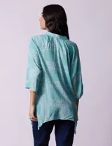 Camisa celeste con estampado de cachemir en blanco, cuello a la base, escote en V y abertura central con botones. Terminación de ruedo asimétrico. Manga 3/4 de largo regulable con presilla y botón.