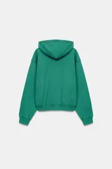 Sudadera con capucha Fruit of the Loom en colaboración con Zara, de color verde con detalles en morado en el interior de la capucha, la cartera de botones y los bordes del bolsillo frontal tipo canguro. Presenta mangas largas, cordones ajustables y un parche con el logo en el centro.