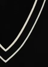 Jersey de punto fino en color negro con cuello de pico y mangas largas. Presenta detalles de líneas blancas en contraste en el borde del cuello y en los puños.