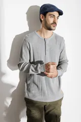 Remera de manga larga gris de tejido waffle, con cuello redondo y cierre frontal parcial de tres botones.