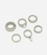 Kit de seis anillos de metal plateado con diseño redondeado y aplicaciones de perlas sintéticas.