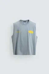 Musculosa de corte relajado con efecto lavado, cuello redondo y sisas amplias. Presenta estampados gráficos en color amarillo en el frente y acabados irregulares que le otorgan una apariencia única.