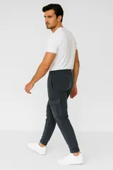 Babucha gris oscuro estilo cargo con cintura elástica y cordón de ajuste, bolsillos laterales con solapa y puños elásticos en los tobillos.