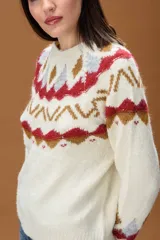 Sweater de punto color crema con diseño de inspiración nórdica y patrones geométricos en tonos rojo, gris y marrón. Presenta cuello redondo, mangas largas y terminaciones acanaladas en puños y bajo.