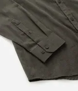 Camisa de manga larga confeccionada en tricolina de algodón, con cuello inglés, cierre frontal de botones y puños abotonados. Diseño liso y versátil.