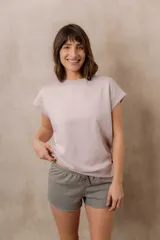 Sweater de punto color blanco, de corte relajado, con cuello redondo, manga corta japonesa de hombro caído y pretina ancha en la cintura.