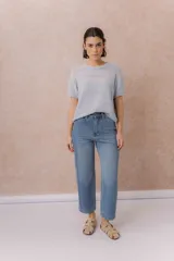 Jean de denim celeste con lavado claro, corte recto y tiro medio-alto, con diseño de cinco bolsillos y cierre frontal con botón y cremallera.