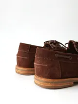 Sandalias de cuero gamuzado color marrón chocolate, diseño tipo huarache con tiras entrelazadas, tira en el empeine, talón cerrado y hebilla metálica de ajuste lateral.